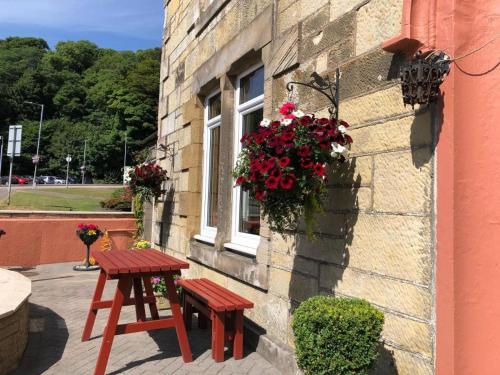 a table and bench next to a building with flowers at Hamilton House Guest House in Oban