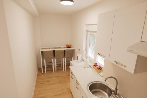 a white kitchen with a sink and a table at Apartmani Otium in Mostar