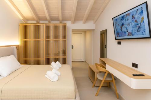 a room with a bed and a desk and a tv at NOBILIS CORFU Hotel in Acharavi