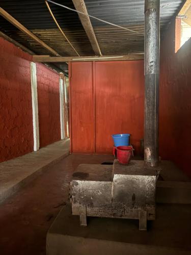 a room with a red wall and two buckets at Tashi Delek Hostel & Homestay in Tawang