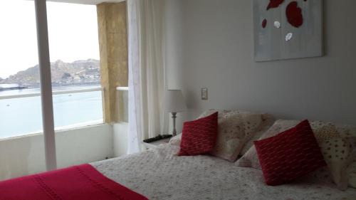 Un dormitorio con una cama con almohadas rojas y una ventana en Ovaser I, en Coquimbo