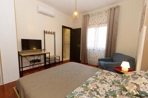 a bedroom with a bed and a television and a chair at Dimora Nicotera in Lamezia Terme
