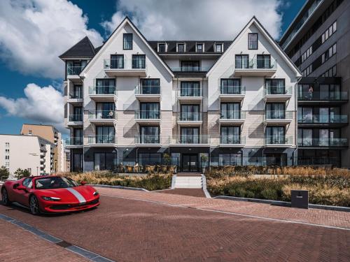 a red car parked in front of a building at Hotel de Schelde in Cadzand-Bad