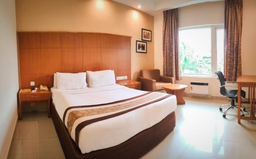 a hotel room with a large bed and a desk at La Franklin Hotel in Bhubaneshwar