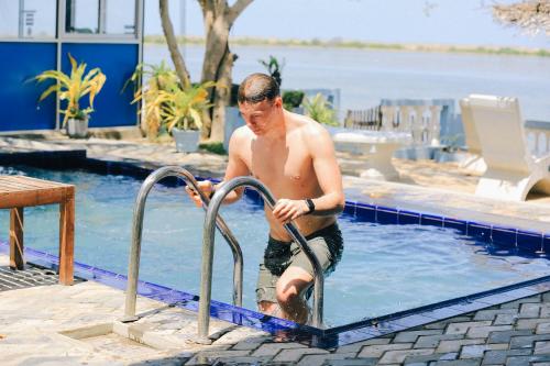 a man in a swimming pool with a rail in the water at Dinuda Lagoon Hotel in Kalpitiya