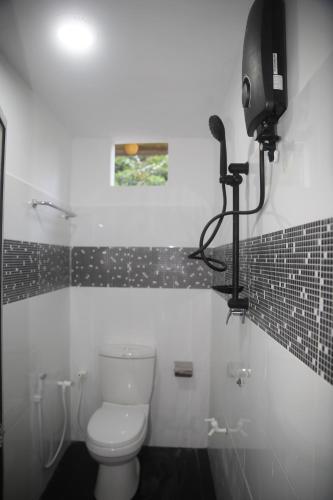 a white bathroom with a toilet and a camera at Sunshine Holiday Inn Ella in Ella