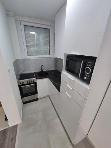 a small white kitchen with a sink and a microwave at Apartman Central Lux in Banja Luka