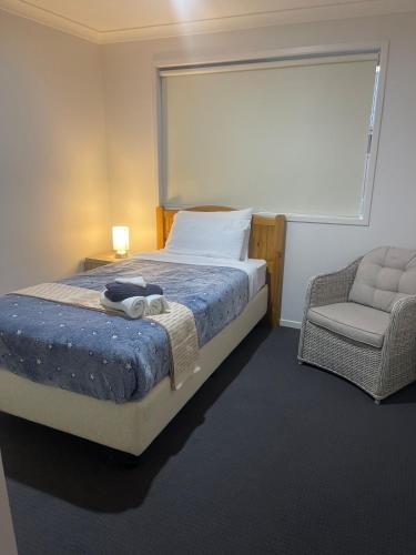 a bedroom with a bed and a chair and a window at Accomodation at Lavington in Lavington