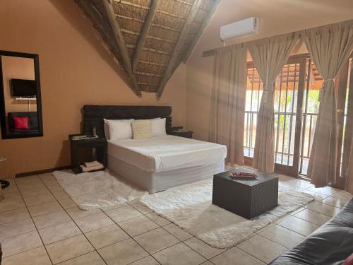 a bedroom with a bed and a couch and windows at VM Guesthouse in Hazyview