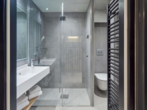 a bathroom with a shower and a sink and a toilet at Aparthotel Adagio Stuttgart NeckarPark in Stuttgart