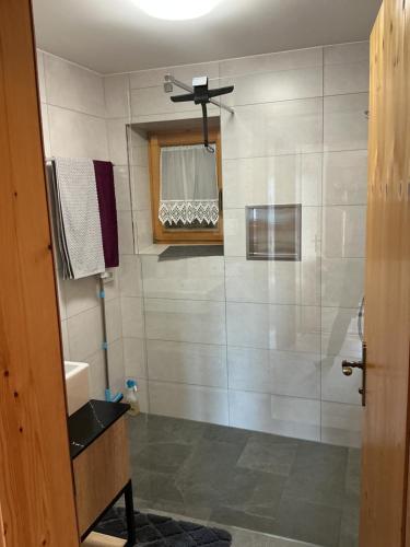 a bathroom with a shower with a sink and a mirror at Haus Natalie in Bartholomäberg
