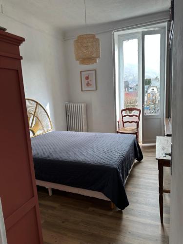 a bedroom with a bed and a large window at Appartement 16 Colette in La Bourboule