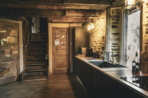 a kitchen with a counter and a sink and a staircase at Le Ranch Normand in Les Cresnays