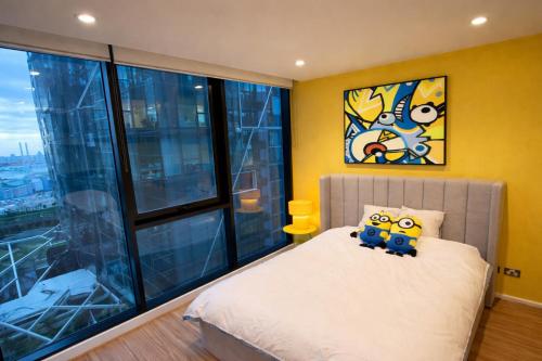 a bedroom with a bed with yellow walls and windows at Banana Bliss - Spacious 2 Bedroom CBD Apartment with 2 Balconies, 2 Bathrooms & Parking Option in Melbourne