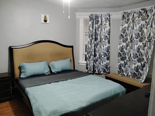 a bedroom with a bed with blue pillows and a window at Grove#8 in Irvington