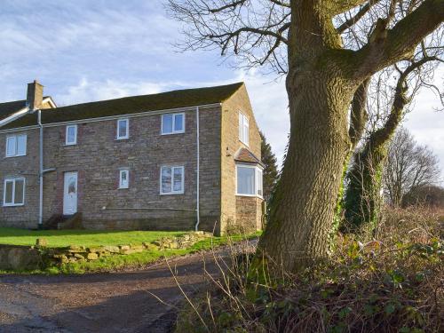 a large brick house with a tree in front of it at Boundary Cottage in Unstone