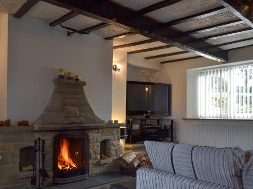 a living room with a fireplace and a tv at Boundary Cottage in Unstone