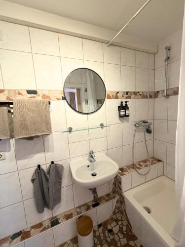 a bathroom with a sink and a mirror and a tub at Gästehaus Stefan Koch in Rust
