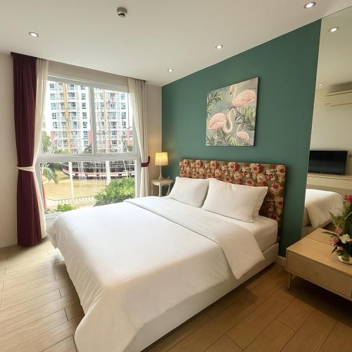 a bedroom with a large white bed and a window at Caribbean Resort Pool Apartments Pattaya Near Bus Terminal in Pattaya South