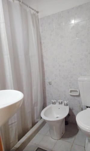 a white bathroom with a toilet and a sink at Cabañas Mai-Hue in El Bolsón