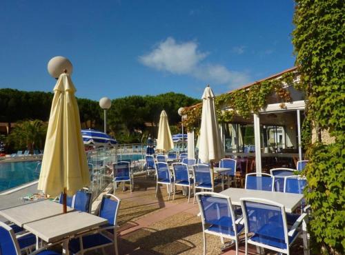 un groupe de tables et de chaises avec des parasols à côté d'une piscine dans l'établissement Studio CAP D AGDE, au Cap d'Agde