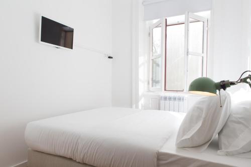 a white bed with a green lamp and a window at Porto Republica Riverside in Porto