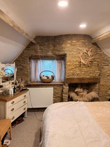 a bedroom with a stone wall with a bed and a window at The loft in Cirencester