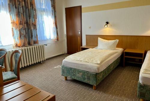 a hotel room with a bed and a chair at Benz Café & Pension in Blankenburg