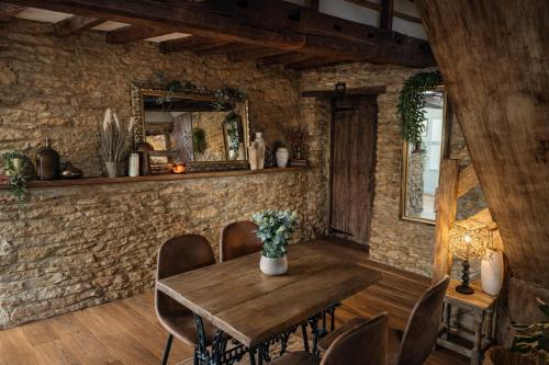 a dining room with a wooden table and a stone wall at The loft in Cirencester