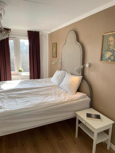 a bedroom with a bed with a headboard and a table at Charming Bed & Breakfast - Villa Högby in Löttorp