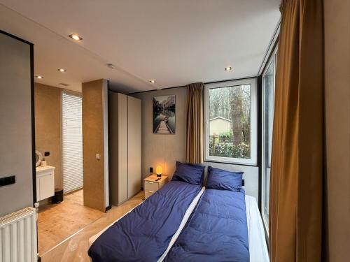 a bedroom with a blue bed and a window at Detached Hoenderloo veluwshof in Hoenderloo
