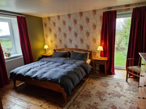 a bedroom with a bed and two windows with red curtains at Barcloy Milk House in Kirkcudbright