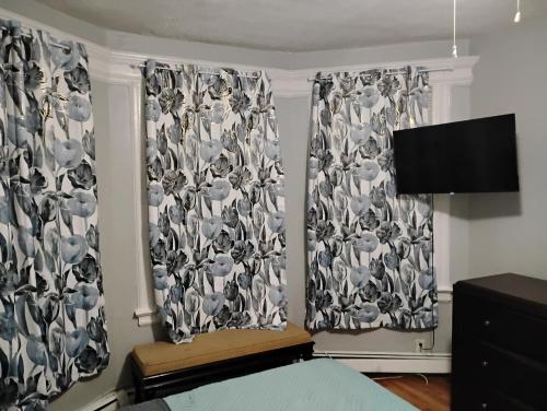 a bedroom with two windows with curtains and a tv at Grove#8 in Irvington