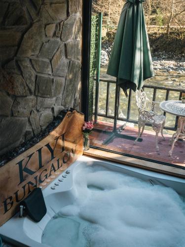 a hot tub next to a patio with a table and an umbrella at Kiyi Bungalov in Çamlıhemşin