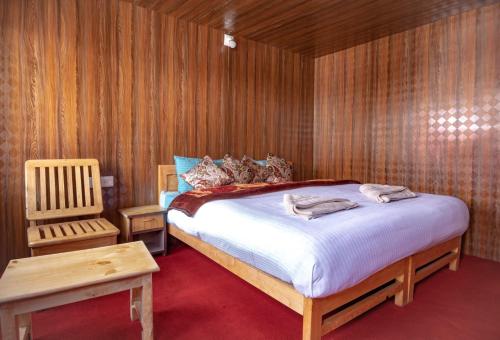 a bedroom with a bed and a wooden wall at Pangong Mentsel Cottage in Lukung