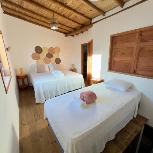 a bedroom with two beds with white sheets at Vila Uryah in Caraíva
