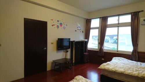 a bedroom with a bed and a tv and a window at Lu He Feng Homestay in Luodong