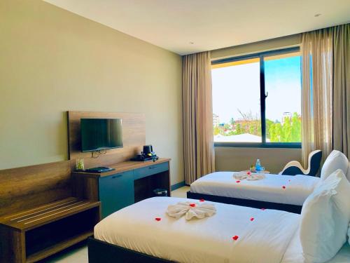a hotel room with two beds and a television at New Amaan Hotel in Zanzibar City