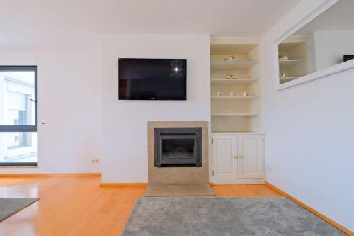 a living room with a fireplace and a flat screen tv at Bright & Modern Duplex with Terrace Telheiras in Lisbon