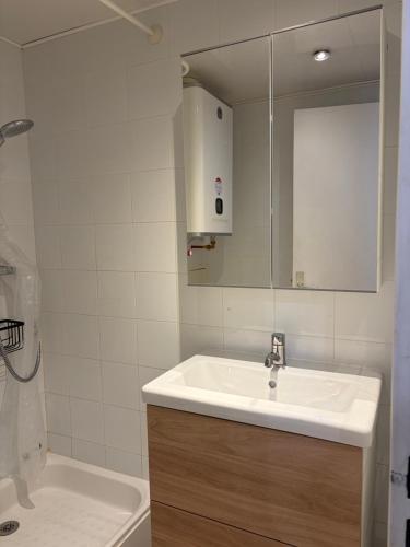 a white bathroom with a sink and a mirror at Studio Tignes Val Claret in Tignes
