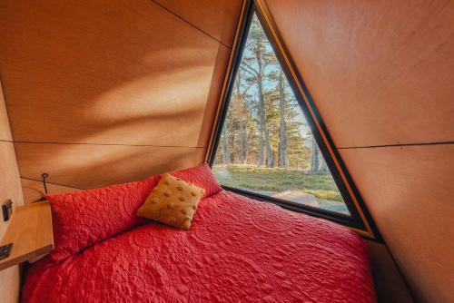 a bedroom with a red bed with a window at Romantic luxury tiny home in an idyllic setting in Glenquarry