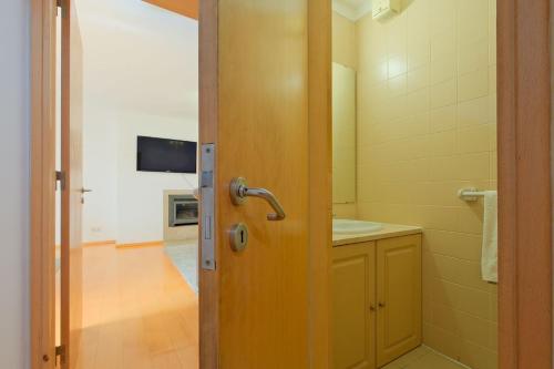 a bathroom with a door with a sink and a television at Bright & Modern Duplex with Terrace Telheiras in Lisbon