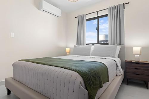 a white bedroom with a large bed and a window at Atabey II – Epic Residence, Bávaro in Punta Cana
