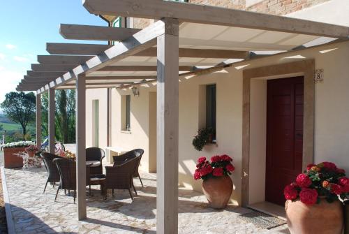 a pergola over a patio with a table and chairs at Le Maraclà Country House in Iesi