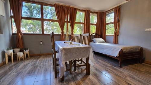 a bedroom with a table and a bed and windows at Cabaña Lumen in Uspallata