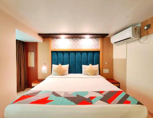 a bedroom with a large bed with a blue headboard at Hotel Aishwarya Residency in Nerul
