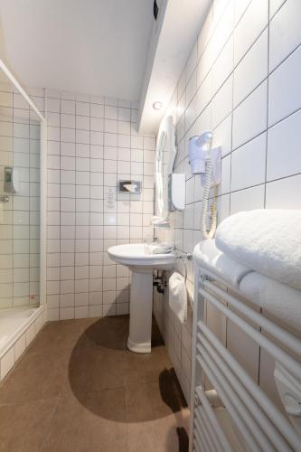 a white bathroom with a sink and a mirror at The Originals Boutique, Hôtel La Ferme du Pape, Eguisheim in Eguisheim