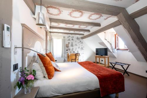 a bedroom with a large white bed with orange pillows at The Originals Boutique, Hôtel La Ferme du Pape, Eguisheim in Eguisheim