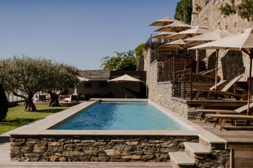 a swimming pool in a yard with umbrellas at Boutique Hotel NOAE by Emerald Stay in Oletta