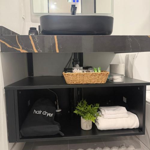 a black shelf with towels and a basket on it at Downtown Luxe Stay - High River in High River